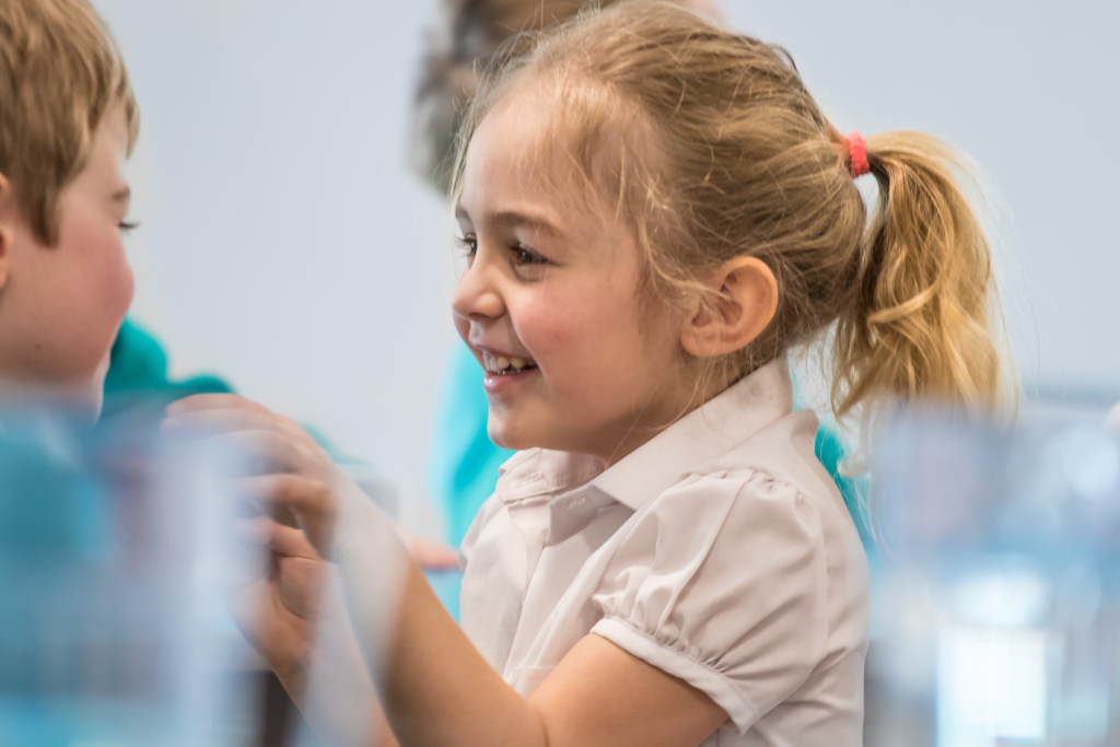 A young girl is shown laughing with her peers.