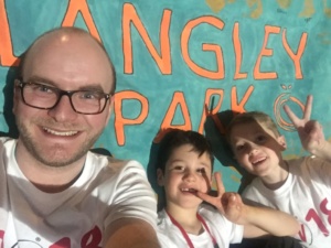 A man and two children smiling posing for a picture. The children have peace signs 